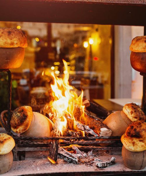 traditional Turkish Testi Kebab cooked in clay pot on open fire at night in restaurant, authentic oriental cuisine